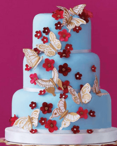 Tarta azul con mariposas y flores rojas